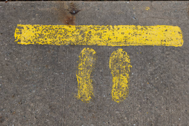 istock Yellow footprints and painted line on a concrete surface indicating a waiting spot in a public area 2193660161