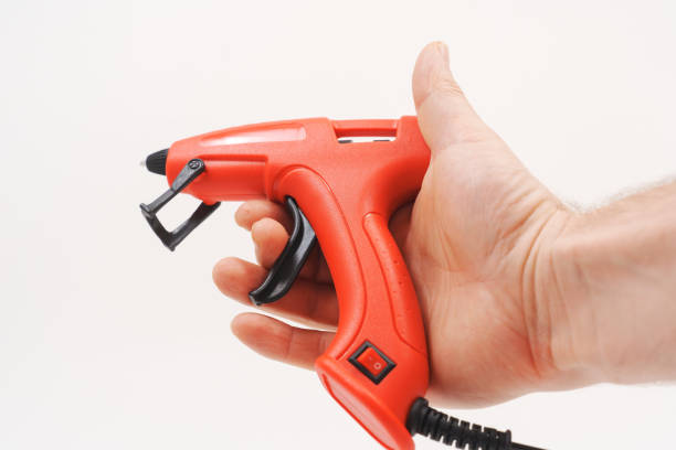 istock A red glue gun with a black wire in hand on a white background. 2193660700