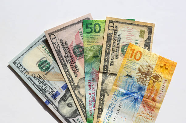 istock US Dollar and Swiss franc banknotes with white background 2193667316