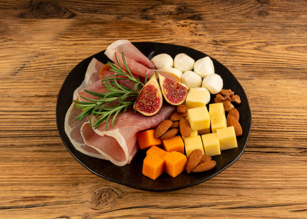 istock Cheese plate with prosciutto, jamon cut, parma ham, serrano slices, cured iberico closeup, cheese board 2193668013