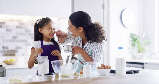 istock Playful, mom and child with kitchen, baking and learning with ingredients for pastry or dessert cake. Smile, happy mother and teaching cooking daughter for pudding, cookies or recipe prepare in home 2193668537