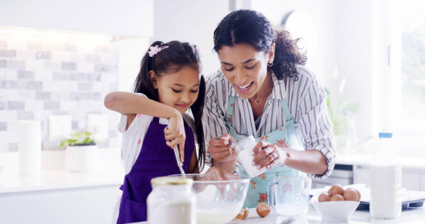 istock Teaching, mother and girl with kitchen, baking and learning with ingredients for pastry or dessert cake. Smile, happy mom and cooking daughter help for pudding, cookies or recipe prepare in home 2193668549