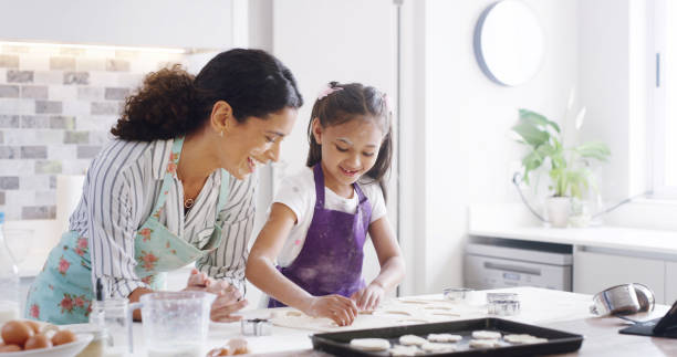 istock Help, mom and child with cookies, baking and learning with ingredients for kitchen dessert and bonding. Smile, happy mother and teaching daughter for support, sweets or bakery recipe prepare in home 2193668746