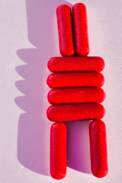Red candies arranged in a stacked formation on a pastel pink surface.
