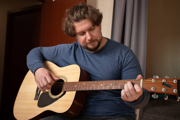 istock Guitarist playing Acoustic Guitar, practicing melody indoor, learning musical skill 2193670326