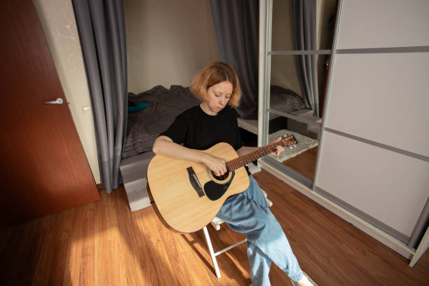 istock music lessons, Woman learning guitar, practicing chords on acoustic guitar, focusing on string technique, indoor musician lifestyle 2193670441