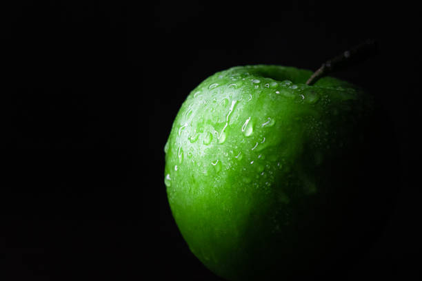 Wet droplets on green granny smith apple with black background. High quality photo