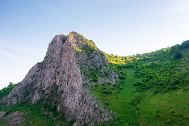 mountain landscape of romania in springtime. wonderful trascau. rock formation and grassy hill in morning light. scenery in valisoarei valley. rocky cliff