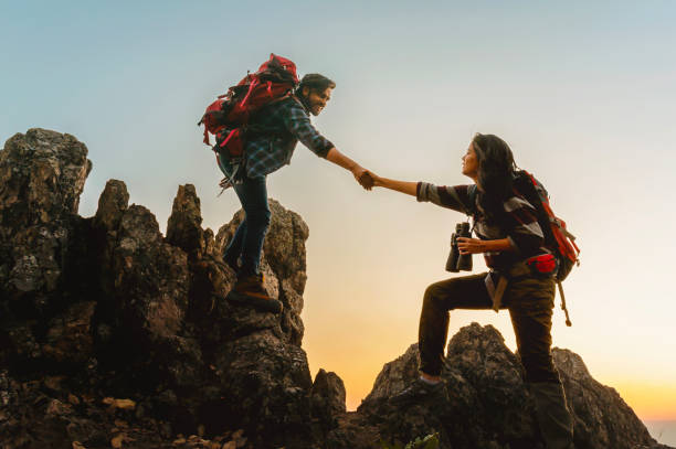 istock man and a woman are helping each other climb a mountain 2193683546