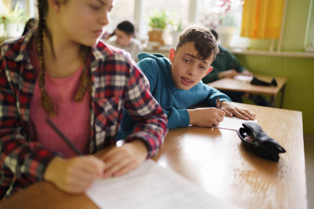 Teenage boy tries to cheating during an exam in the classroom