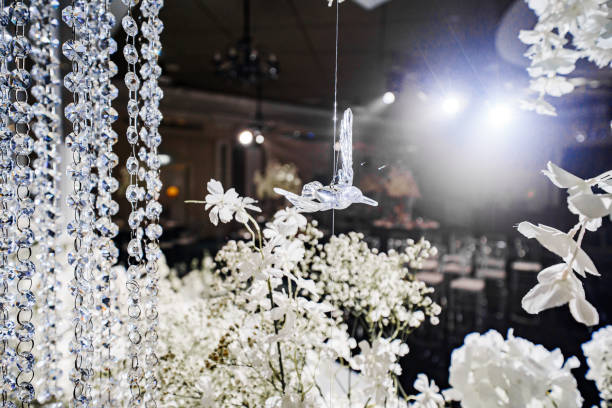 Banquet hall decor for a wedding. White flowers, mirrors and lighting. table setting and services of professional event organizers. glass bird.