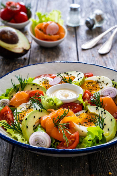 istock Smoked salmon with hard-boiled egg, avocado and leafy vegetables on wooden table 2193688134