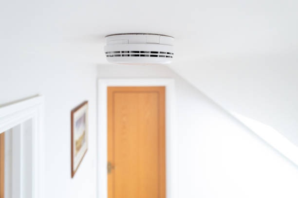 Ceiling view of a newly installed smoke detector seen on the first floor of a new show home. stock photo