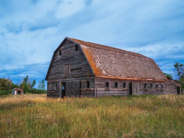istock Rustic wooden barn stands in a grassy field under a vibrant blue sky. 2193690903