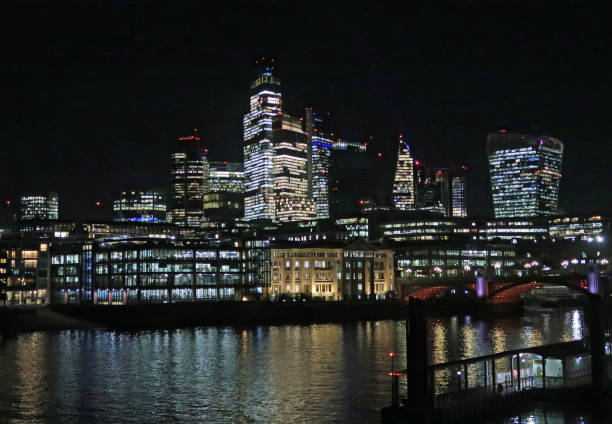 London, United Kingdom, November 26, 2024. City of London financial district skyscrapers illuminated at night. From Southbank of the river Thames. Outdoors on a dark winter night.