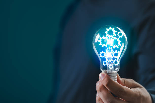 istock Hand holding light bulb with glowing gears symbolizing ideas, innovation, and technology. Blue background. Concept of creativity and invention. 2193698156