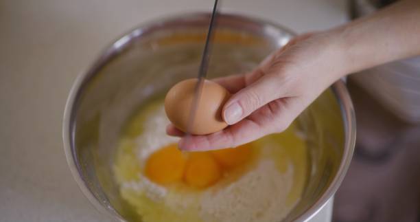 istock Close-up of cracking raw egg into bowl breaking egg with knife 2193698573