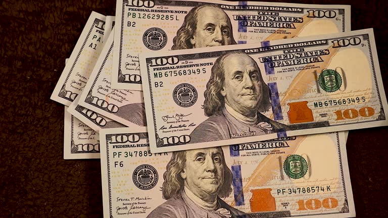 Crisp $100 bills drop one by one, forming a neat stack of $1,000. The slow, mesmerizing fall highlights the elegance of money and the allure of wealth in a close-up view.