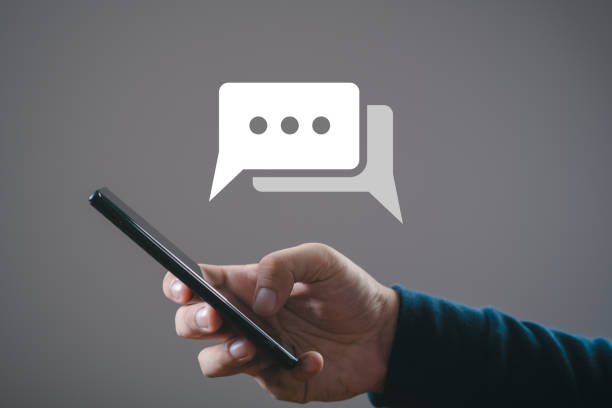 istock Hand holding a smartphone with a chat bubble icon on the screen, representing online texting, messaging, or communication concept. 2193699221