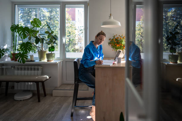 istock Focused woman comfortable works at home by writing notes in day planner sits at table with laptop. 2193701210