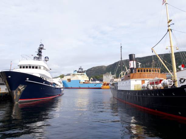 Bergen, Norway – September 14, 2024: A serene harbor scene featuring luxury yachts and historic ships against a mountainous backdrop in Bergen, Norway.