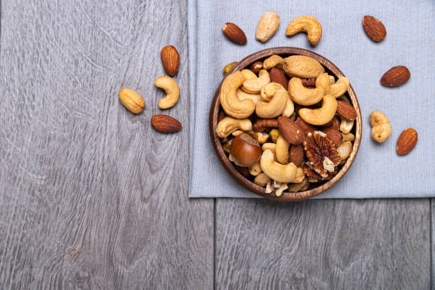 istock various nuts in a wooden bowl on gray surface. space for text 2193701535