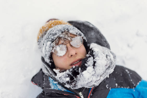 Child wearing warm winter clothing playing in a snow covered field