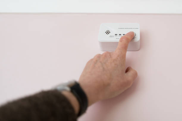 Homeowner seen doing a weekly test for an installed generic Carbon Monoxide located in a kitchen. stock photo