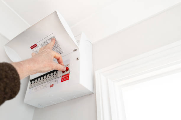 Electrician seen about to switch off the Main Switch for electricity into a typical house. stock photo