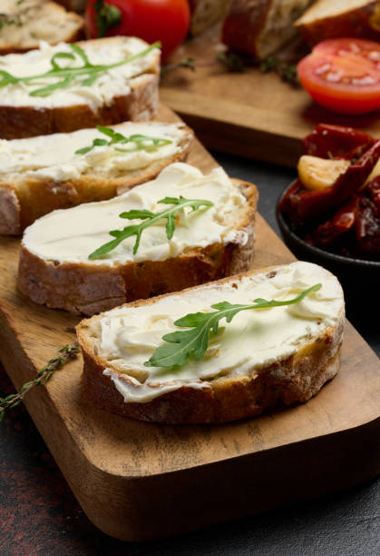 istock Cream cheese spread on ciabatta pieces and decorated with arugula leaves, appetizer 2193705370