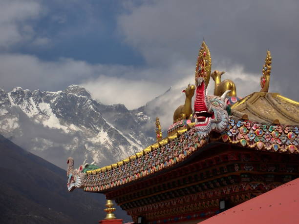 A snow-capped mountain peak seen behind colorful prayer flags in a mountainous region.