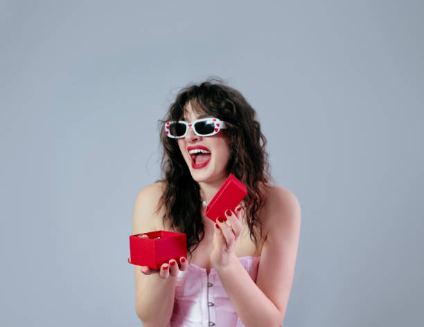 istock A delighted girl opens a gift box, joyfully looking at her present for Valentine's Day celebration. 2193707634