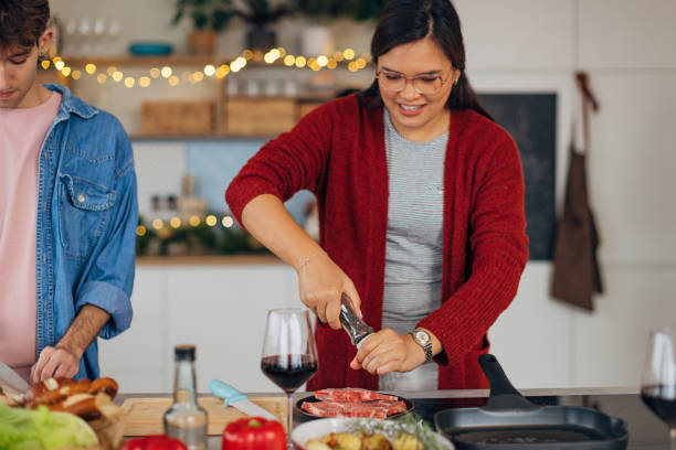 istock Smiling Asian woman adding salt on sliced meat in the kitchen while preparing Christmas lunch 2193708055