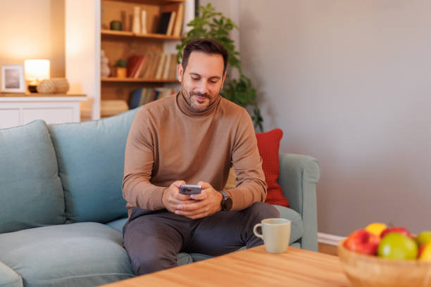 istock Portrait of confident businessman texting over smart phone while sitting on sofa and working from home 2193721130