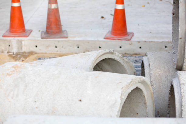 Orange cone warning for cracked concrete drain cover on the cement road.