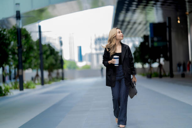 istock Businesswoman standing in a modern urban setting, holding her bag with a confident expression, representing professionalism, elegance, and readiness in a sleek and dynamic environment. 2193723275