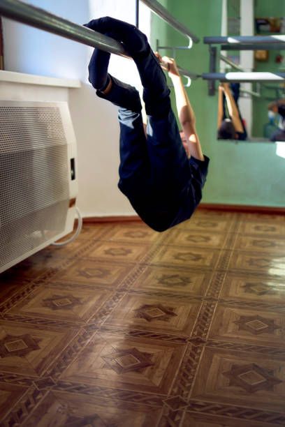 Full length / one man only / rear view of 20-29 years old adult handsome people / short hair caucasian young men / male acrobat / dancer breakdancing / dance music / dancing / upside down / handstand / agility / exercising in front of white background wearing t-shirt / shirt / sports shoe / high tops who is serious / confidence / concentration / cool attitude and being active with sports training / hip-hop