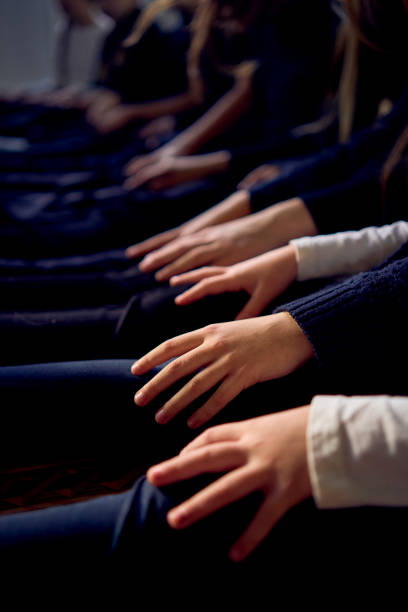 group of pre-teens perform a teacher's task during an acting class , play on the legs of other participants like a piano