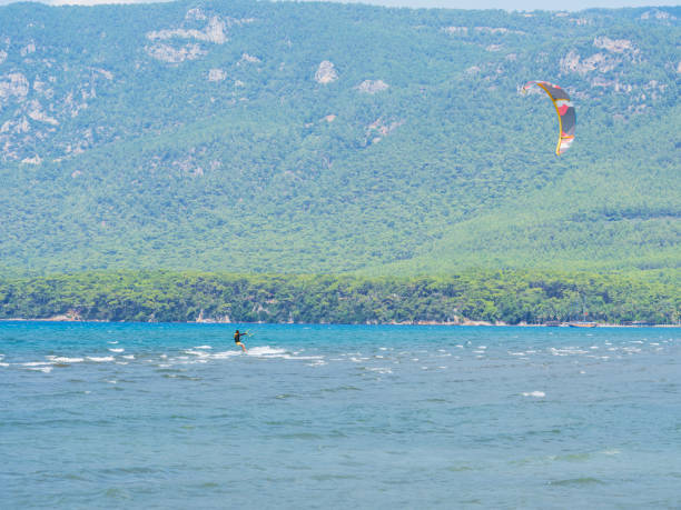 A lone kitesurfer riding the waves on an empty beach.