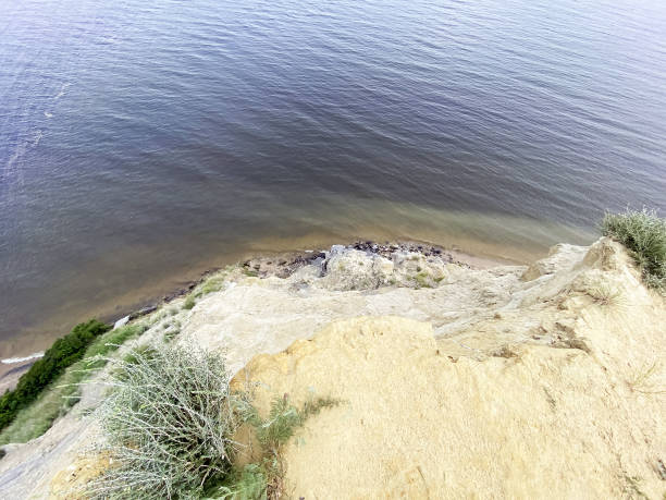 looking down from the edge of a high cliff above the water.