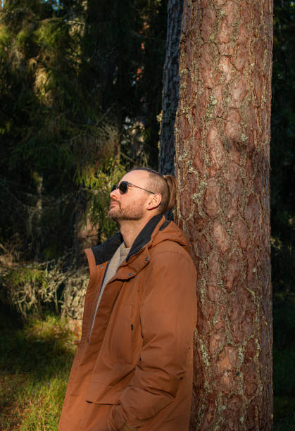 smiling handsome young man finds mushroom in deep pine forest in autumn