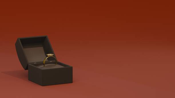istock A minimalist scene featuring a black jewelry box containing a gold engagement ring, standing out against a bold red background. Perfect for themes of proposals, gifts, and luxury 2193728711