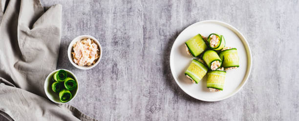 istock Cucumber rolls with fish salad on a plate on the table top view web banner 2193732988