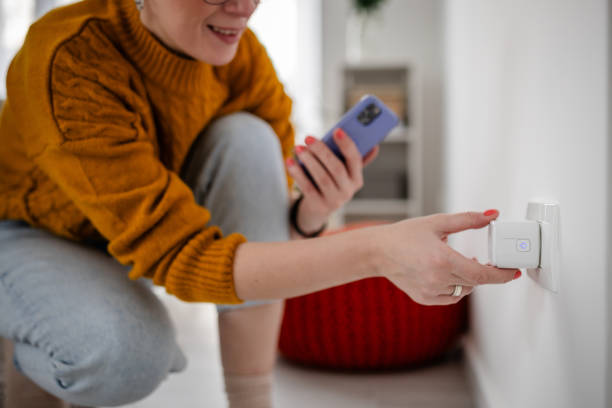 istock Inquisitive woman examines smart device at wall. 2193734869