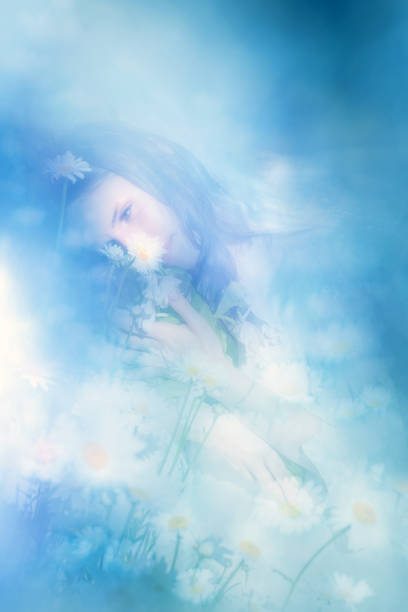 A young, lovely women with a dreamy expression near Daisies, holds a bouquet of white Tulips close to her.