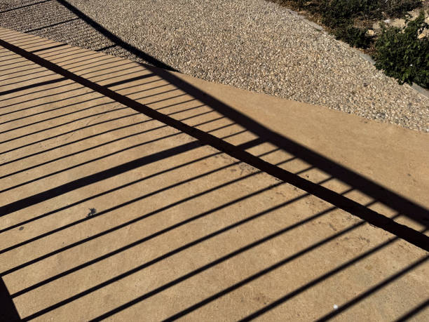 istock Geometric shadows on sunlit concrete path with gravel border 2193736900