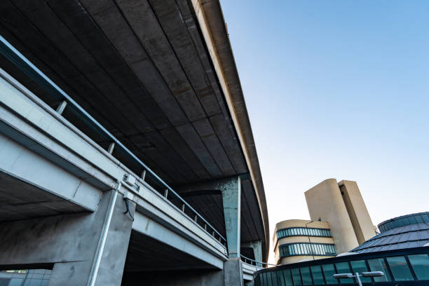 Low angle view of a highway overpass arching over contemporary buildings against a clear blue sky