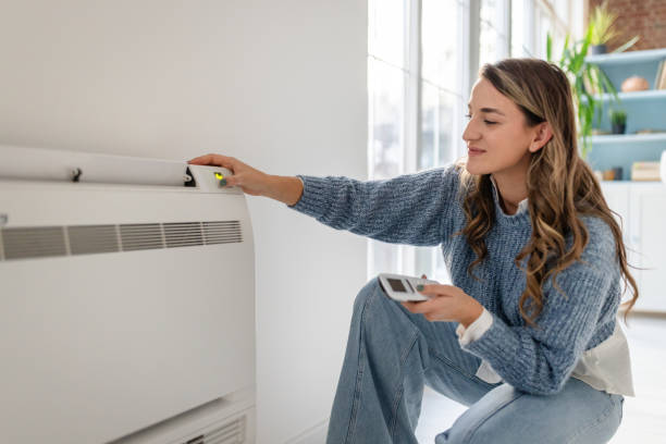istock Woman smiling adjusting air conditioner with remote. 2193738706