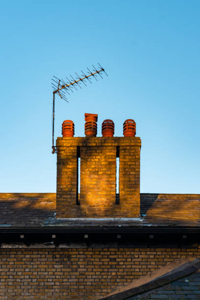istock Brick chimney and tv antenna on rooftop at sunset 2193740268