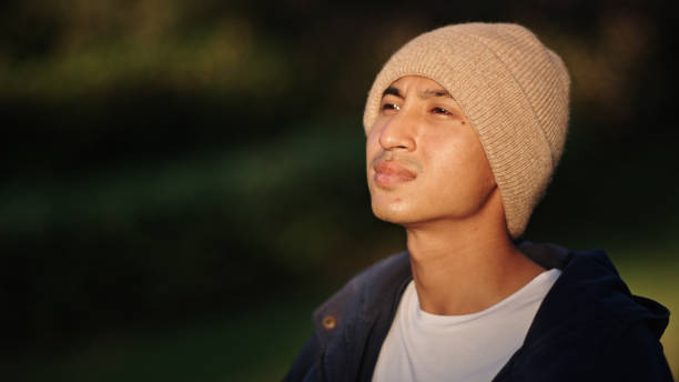 Asian man patient enjoy sunlight while sitting on wheelchair in the park.